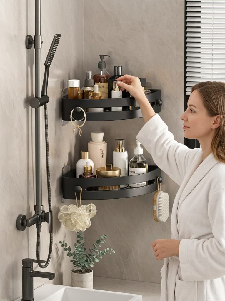 Matte black wall-mounted corner shower caddy with two tiers and hanging hooks, installed in a modern bathroom. Wholesale bathroom organization accessories manufactured by Kaiteng Daily in Yiwu, China, available for OEM bulk orders.